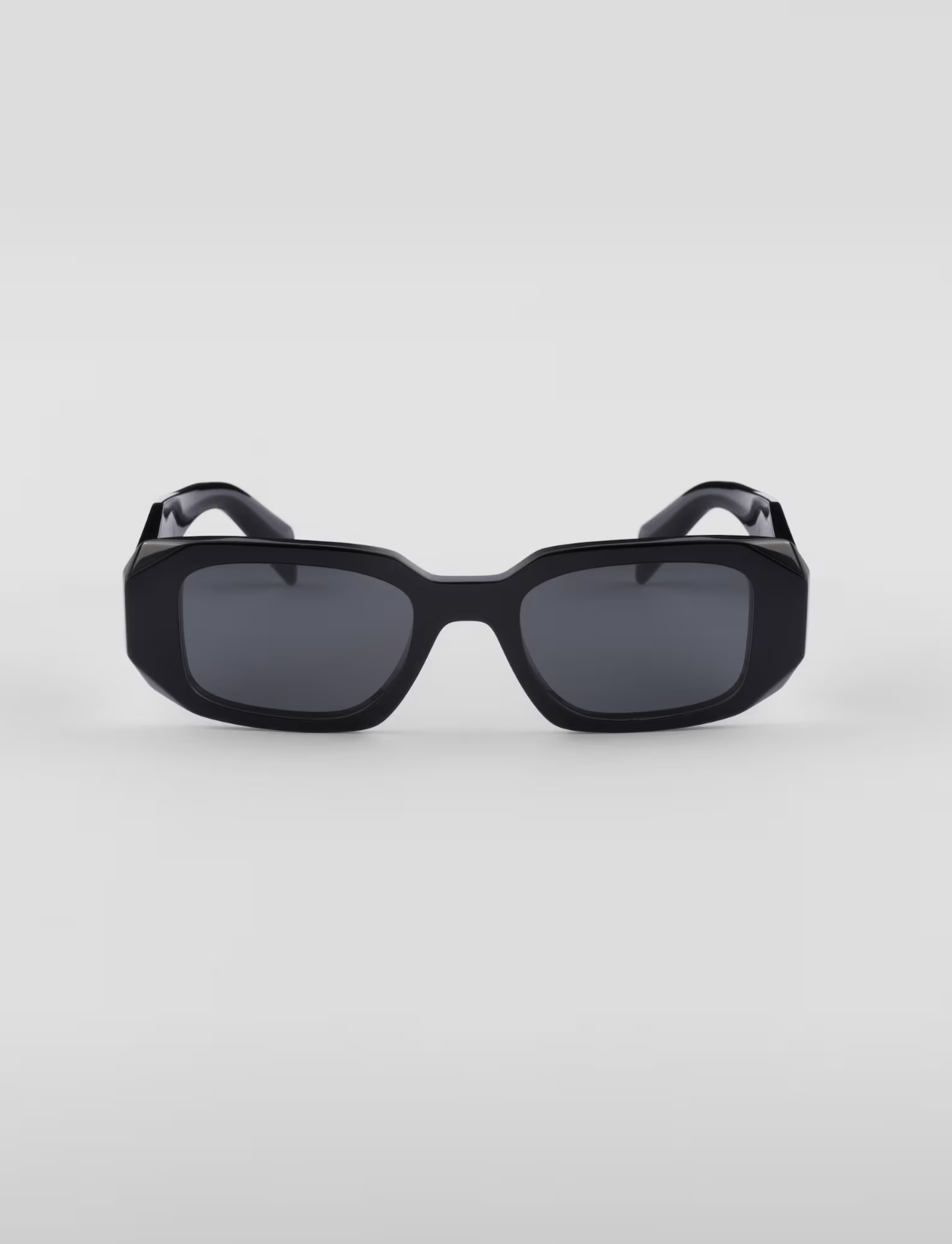 A pair of black sunglasses are sitting on a white surface.