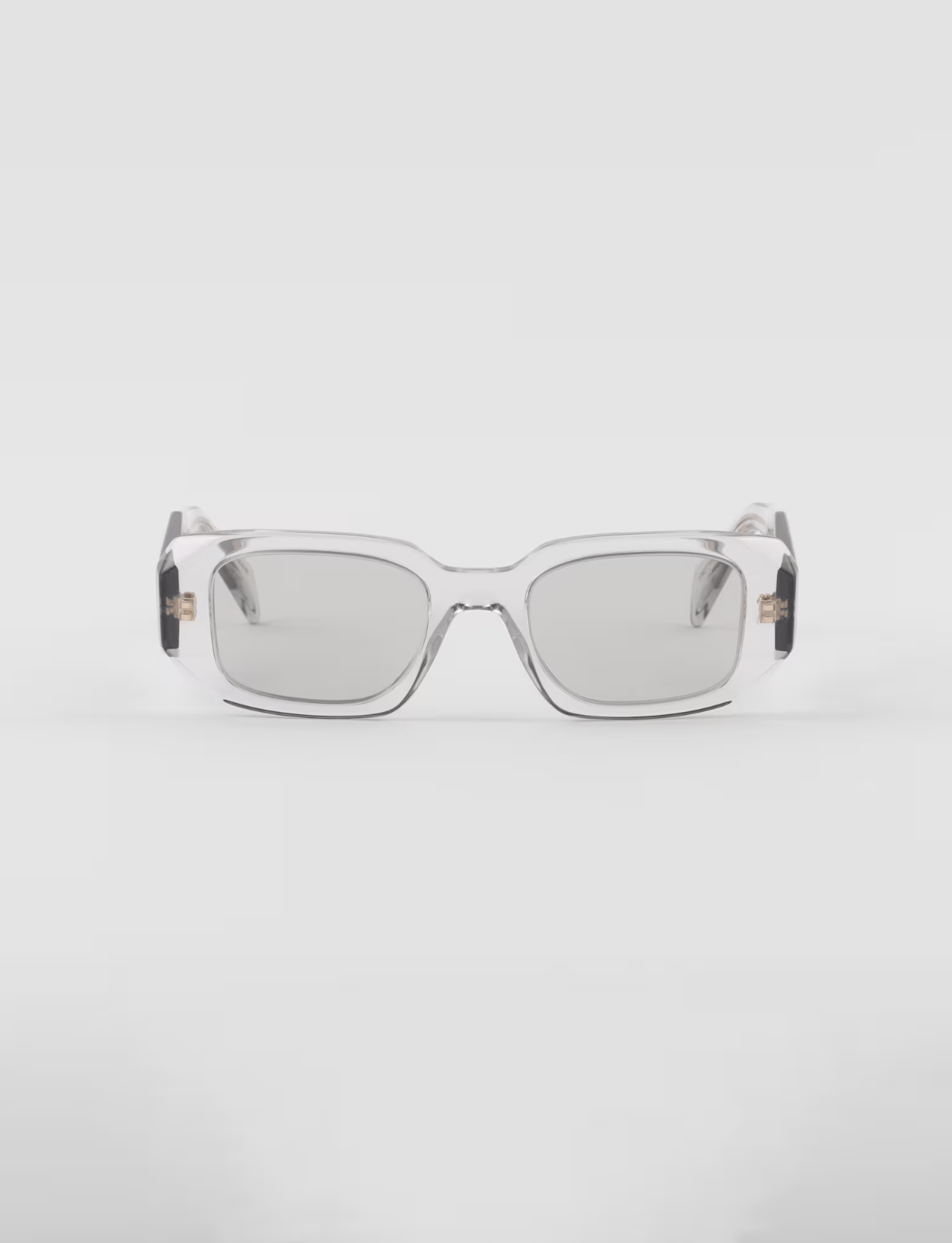 A pair of clear square sunglasses on a white surface.