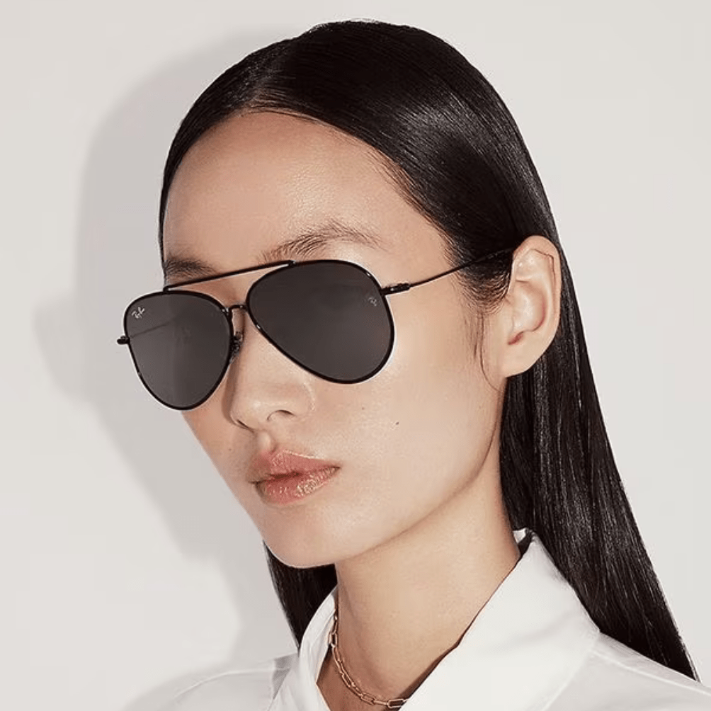 A close up of a woman wearing sunglasses and a white shirt.