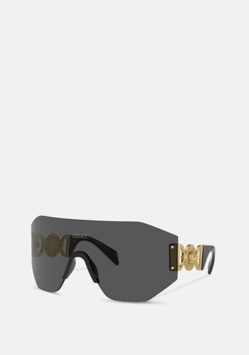 A pair of black sunglasses with a gold logo on the side on a white background.