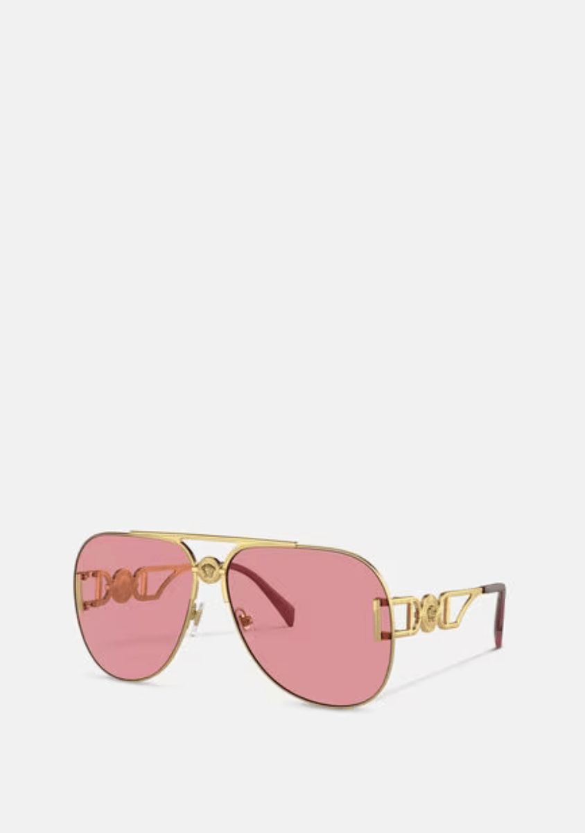 A pair of pink sunglasses with a gold frame on a white background.