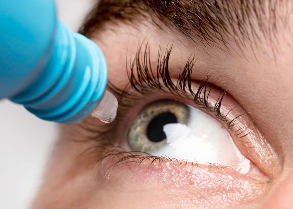 a close up of a person applying eye drops to their eye