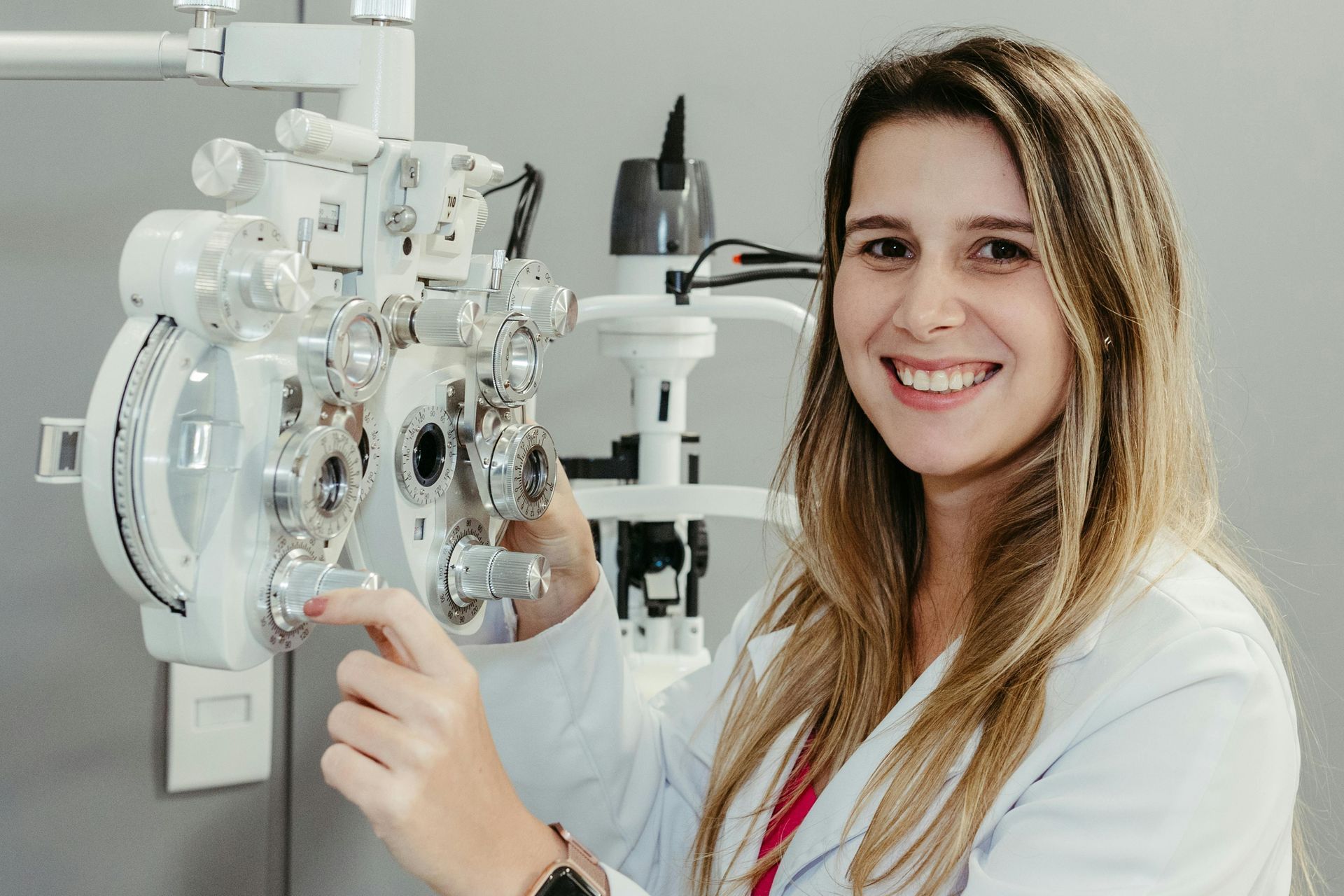 Une femme en blouse de laboratoire tient une machine et sourit.