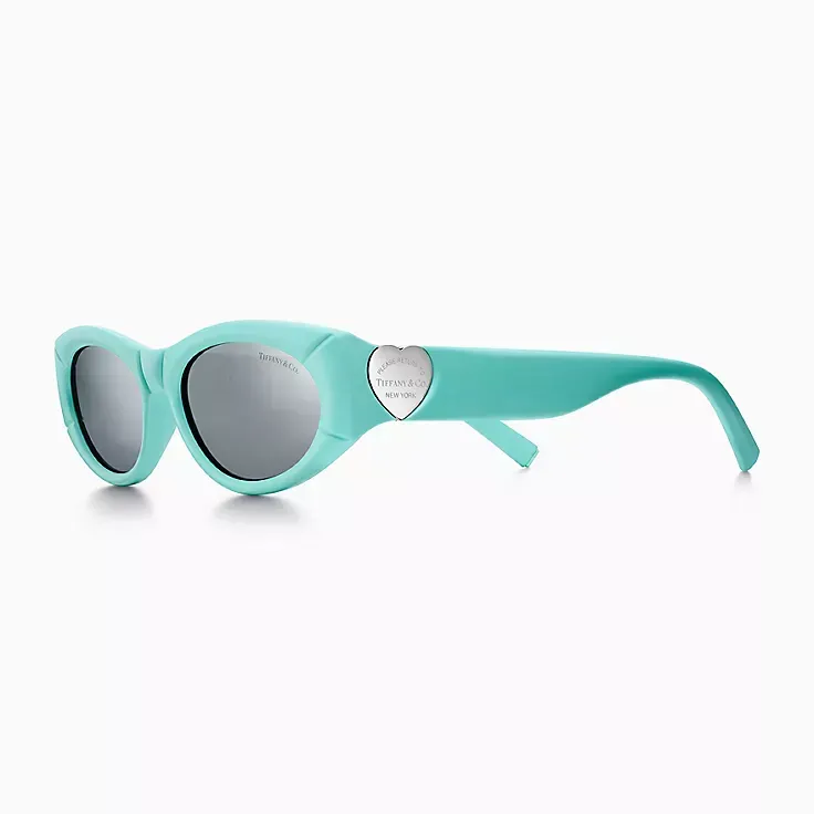 A pair of blue sunglasses with a heart on the side on a white background.