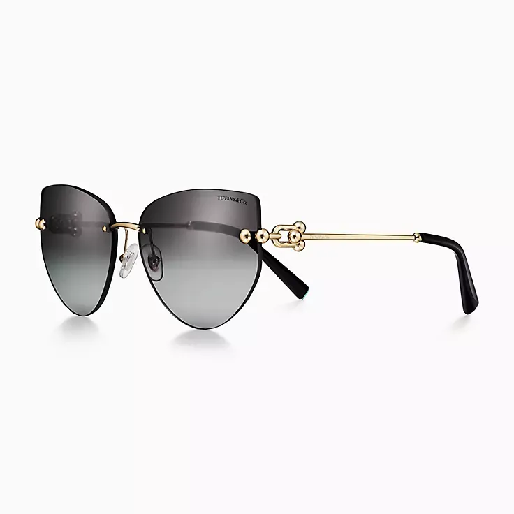 A pair of cat eye sunglasses with a gold frame on a white background.