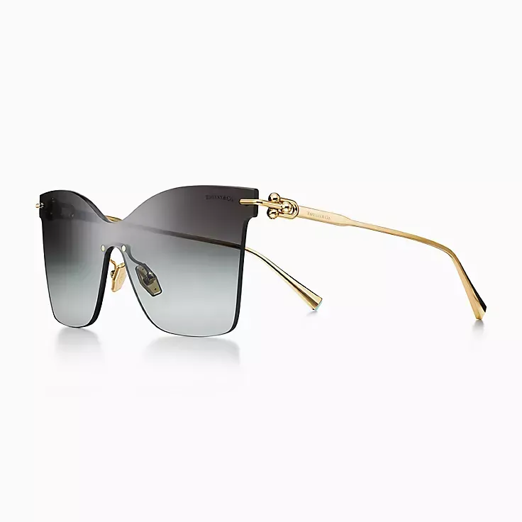 A pair of sunglasses with a gold frame on a white background.