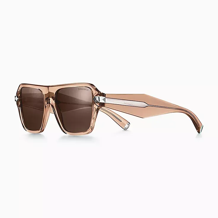 A pair of sunglasses with a clear frame and brown lenses on a white background.