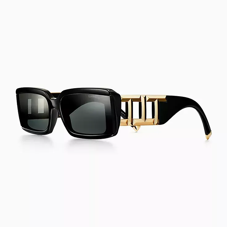 A pair of black sunglasses with a gold frame on a white background.