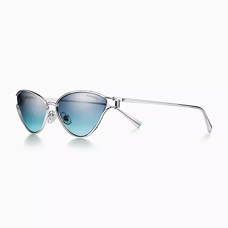 A pair of cat eye sunglasses with blue lenses on a white background.