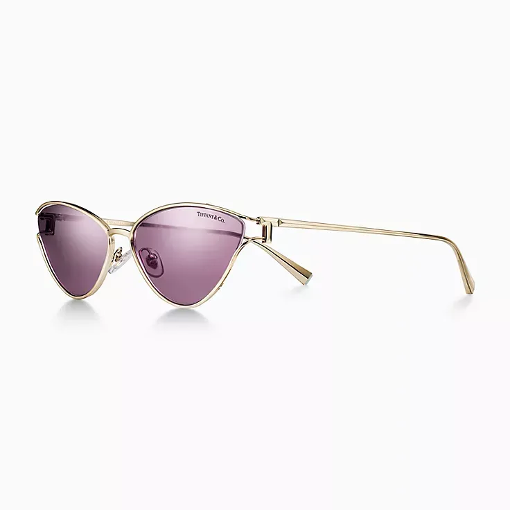 A pair of sunglasses with purple lenses and a gold frame on a white background.