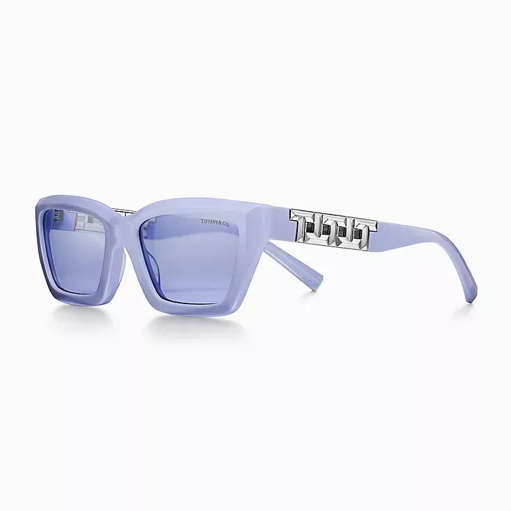 A pair of sunglasses with a purple frame and blue lenses on a white background.