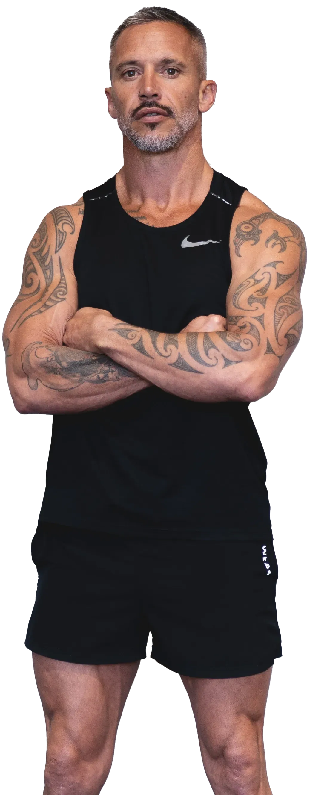 A man with tattoos on his arms is standing with his arms crossed. TBW FITNESS