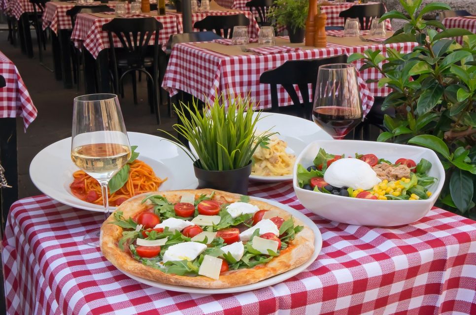 tavolo di un ristorante con pizza, insalatona e piatti di spaghetti