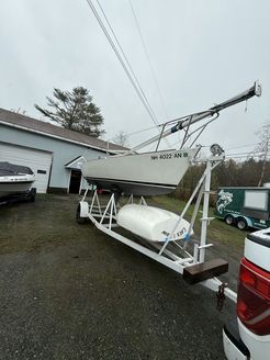 A boat is sitting on a trailer next to a truck.