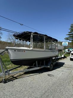 A boat on a trailer is parked on the side of the road.