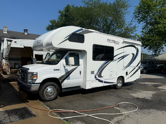 White RV parked outdoors with black and blue decals.