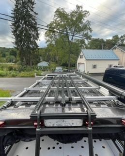 Roof rack on vehicle, with ladder and equipment in a residential setting.