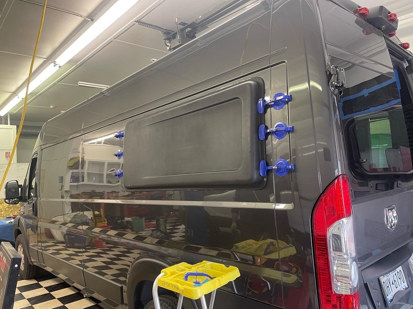 Dark gray van with an installed window; blue suction cups holding window frame.