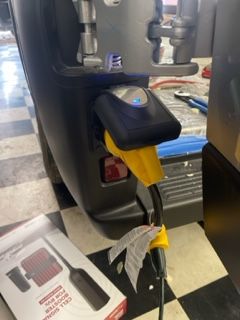 Yellow charging cable plugged into a black device on a vehicle.