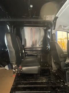 Interior of a black van with a rear row of black seats.