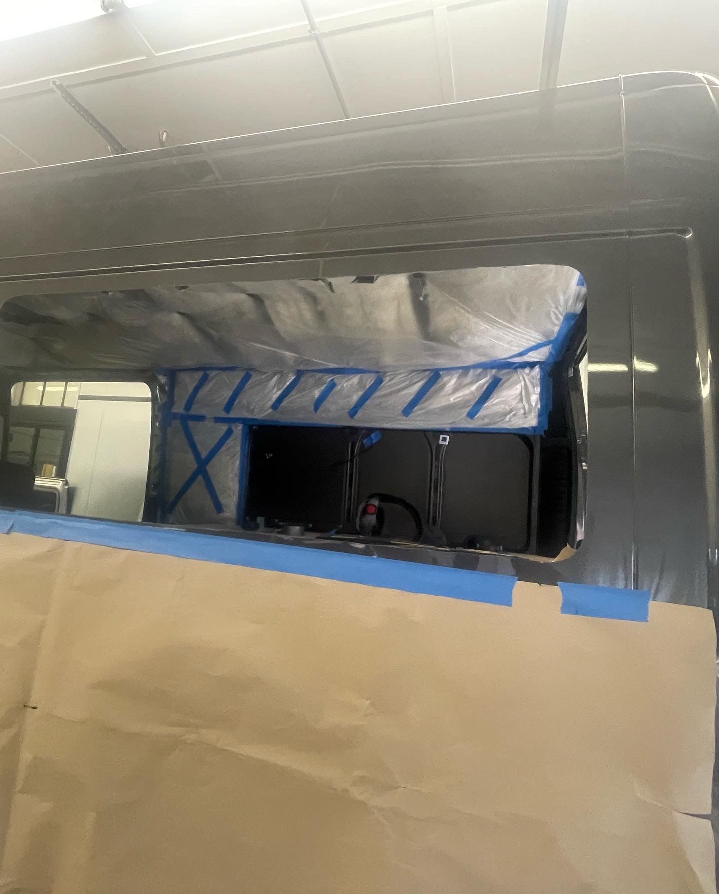 Van window frame taped off for painting. Inside the garage.