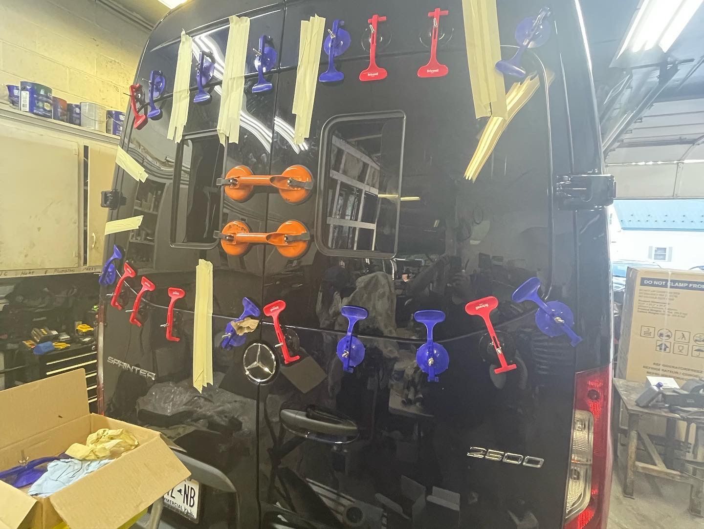 Black van rear with suction cup dent repair tools attached.