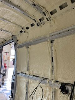 Interior of a van insulated with expanding foam, beige color. Walls, ceiling and metal frames are covered.