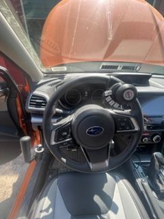 Interior of a Subaru car, with modified steering wheel for adaptive driving. Orange car.