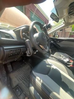Interior view of a car's driver's seat with hand controls installed on the steering wheel.