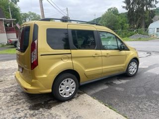 Gold Ford Transit Connect van parked on pavement.