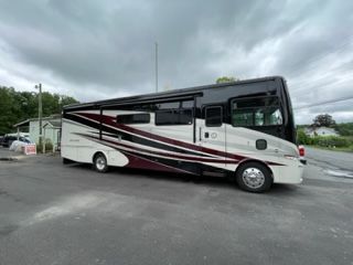 Large white RV with black and maroon accents parked on asphalt.