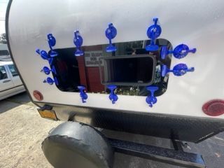 Blue suction cups securing a window in a white camper trailer.