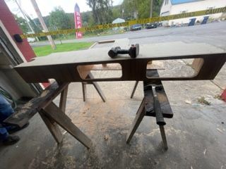 A large brown wooden structure on saw horses with tools in an outdoor setting.