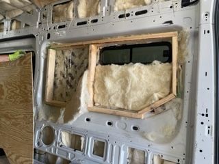 Van interior with insulation and window frame installation.