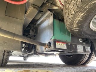 Undercarriage of a vehicle, showing a teal generator, tires, and various mechanical components.
