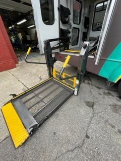Assistant helping disabled person on wheelchair with transport using accessible van ramp