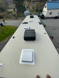 RV roof with vents and air conditioning units, viewed from above, outdoor setting.
