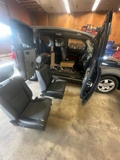 Black Honda Element, doors open, seats removed, in a garage.
