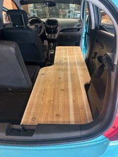 Wooden platform extending from back to front seat inside a blue car.