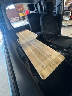 Wooden platform built inside a car for extended cargo space. Seats and interior in view.
