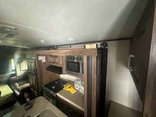 Interior RV view: kitchen with microwave, stove, cabinets, and a counter.