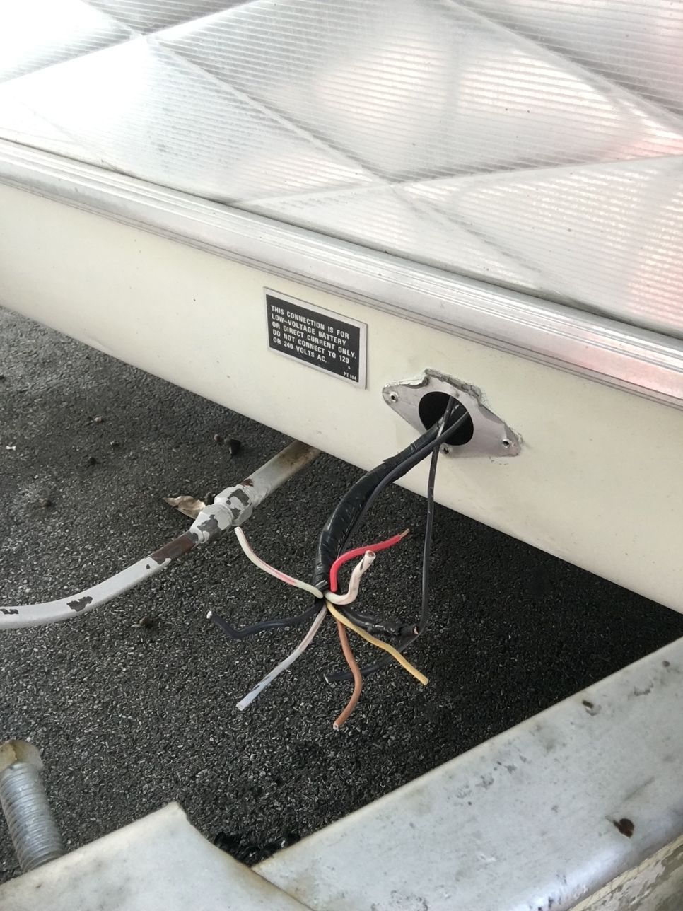 Trailer with exposed wires protruding from a metal fitting.