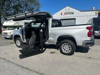 Silver pickup truck with adaptive door for wheelchair access, parked outdoors.