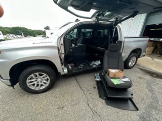 Silver pickup truck with a modified interior for accessibility; a seat is on a ramp.