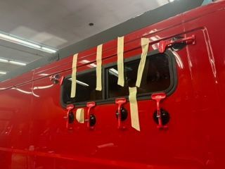 Red vehicle with a window, taped up. Black latches below.