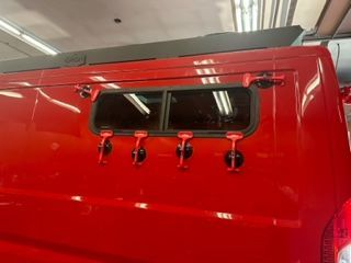 Red van exterior with a window and four red latches.