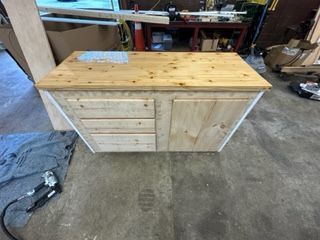Wooden cabinet with drawers and door; light wood countertop, indoors.