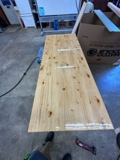 Wooden tabletop with glue applied. A person is nearby.