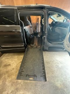 Black wheelchair accessible van with ramp extended. Interior visible.