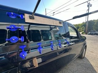 Blue suction cups attached to the side of a black van, possibly for glass installation.